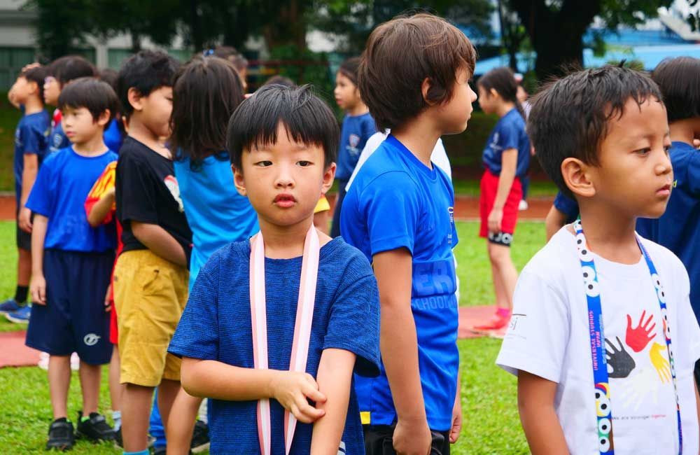 A group of children are standing in a line on a field.