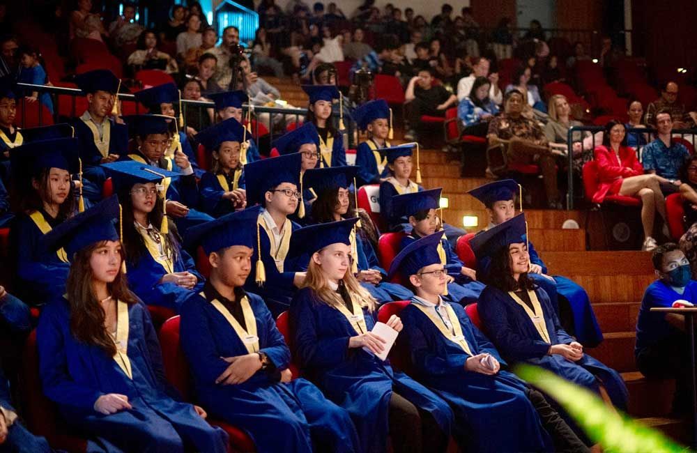 A group of graduates are sitting in a auditorium.
