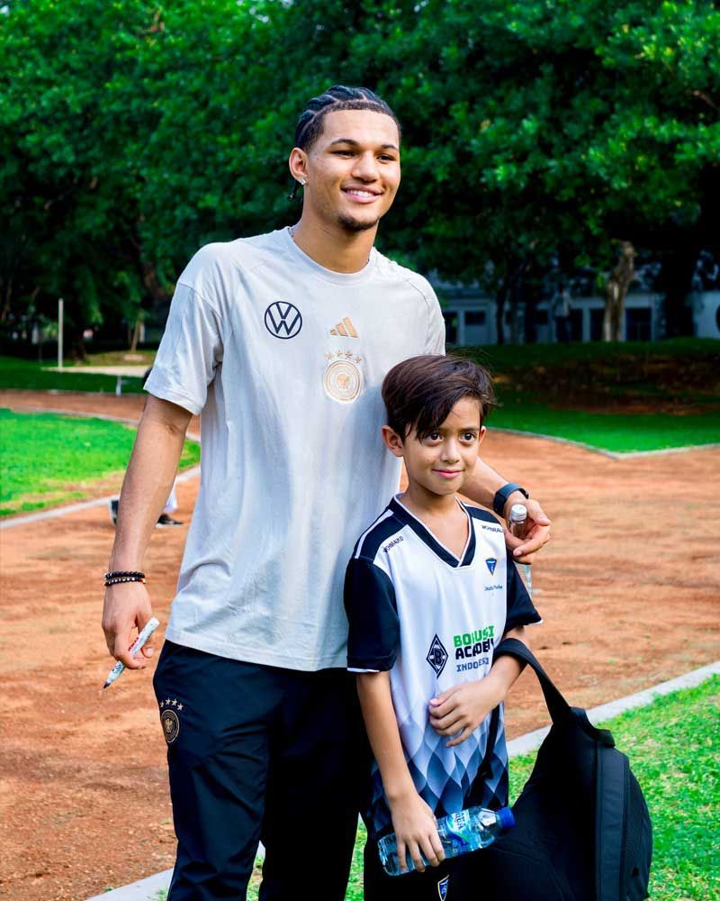 A man and a boy are standing next to each other on a dirt field.