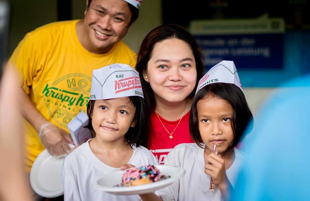 A family is posing for a picture while holding a plate of food.