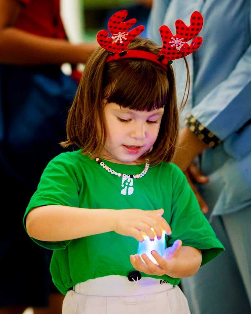A little girl wearing reindeer antlers and a green shirt