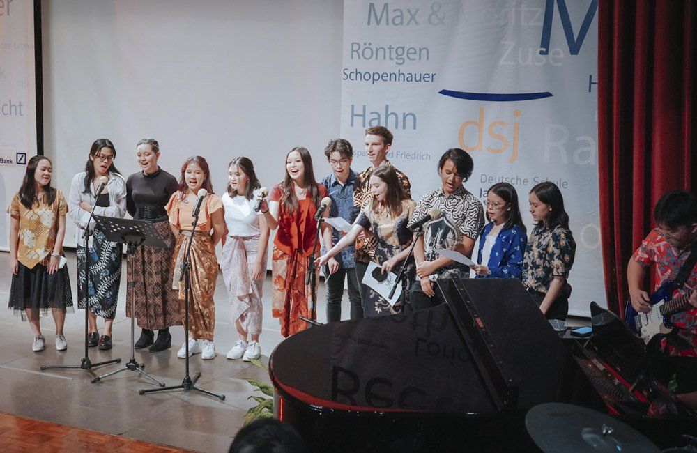 A group of people are standing on a stage singing into microphones.