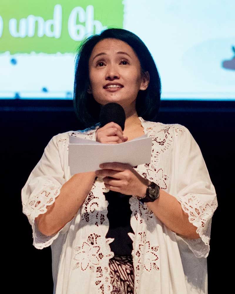 A woman is holding a microphone in front of a sign that says und