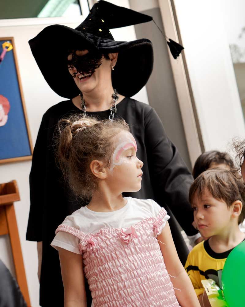 A woman in a witch costume is standing next to a little girl in a pink dress