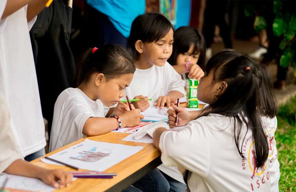 A group of young girls are sitting at a table drawing.