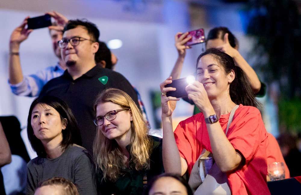 A group of people are taking pictures with their cell phones.