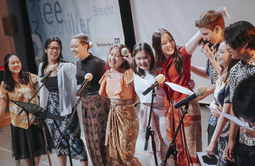 A group of people are singing into microphones on a stage.