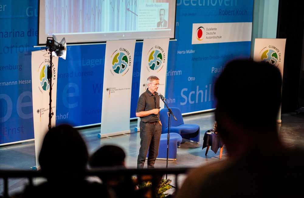 A man is standing on a stage talking into a microphone.