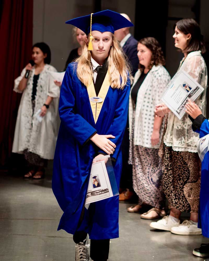 A woman in a graduation cap and gown is walking down the aisle