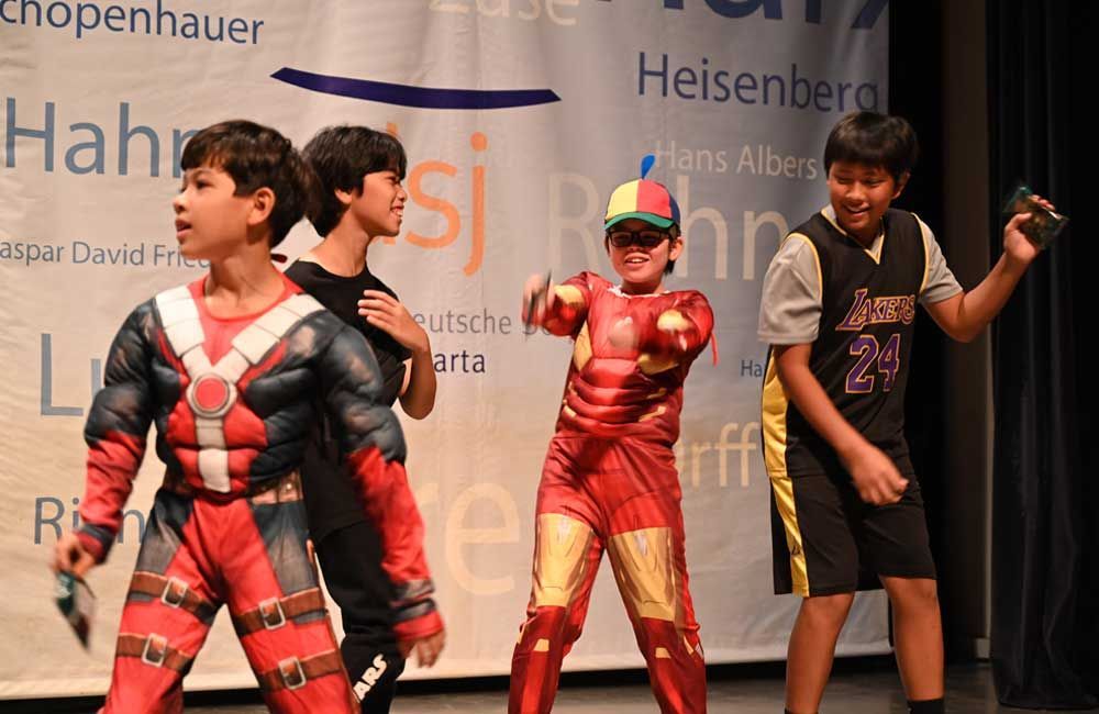 A group of young boys dressed in costumes are dancing on a stage.