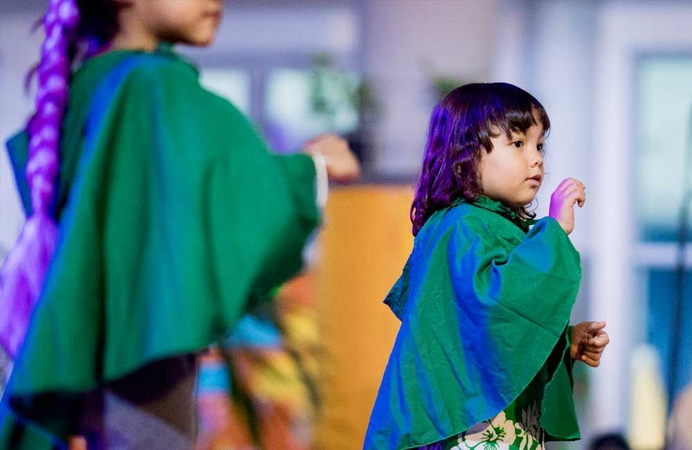 Two little girls are dancing together on a stage.