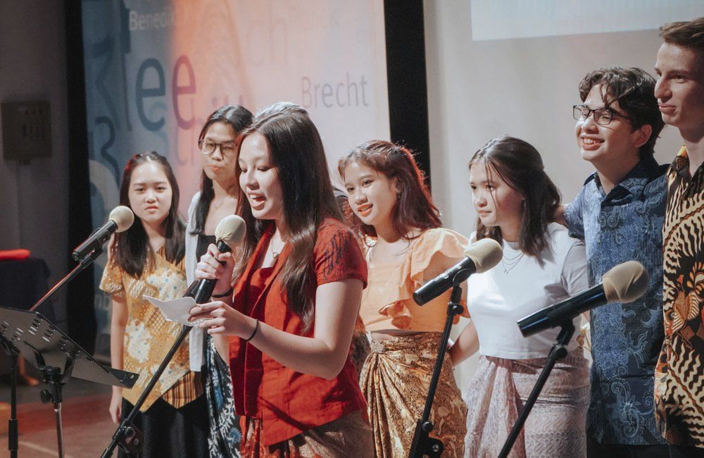 A group of people are singing into microphones on a stage.