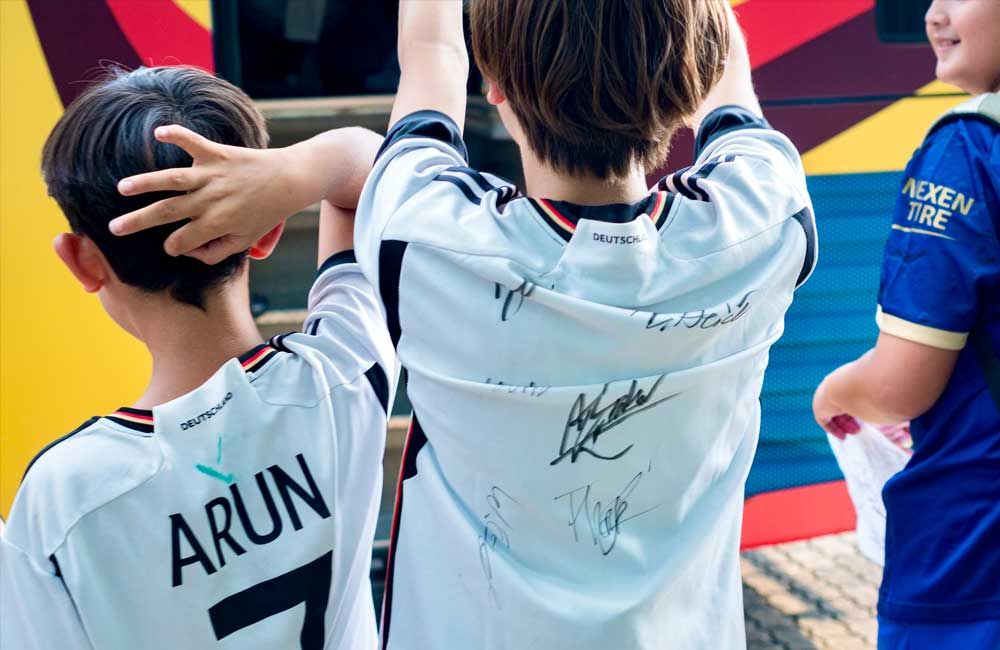 A boy wearing a white jersey with the name arun on it
