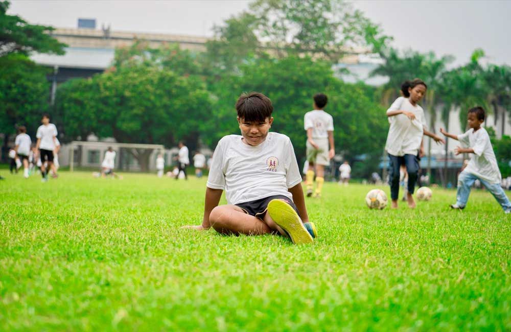 A boy is sitting on the grass with a soccer ball.