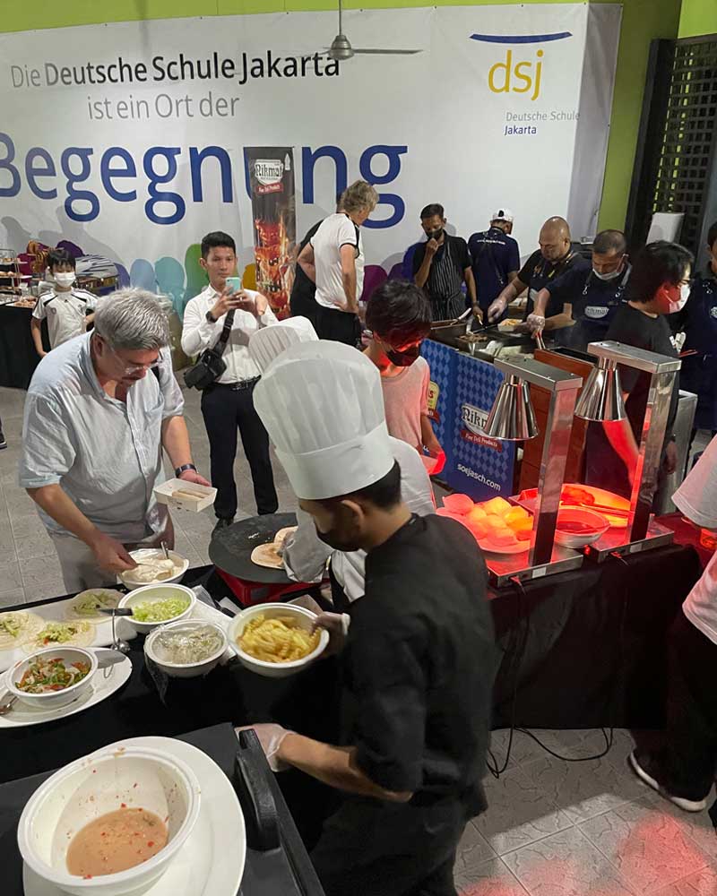 A group of people are standing around a table with bowls of food.
