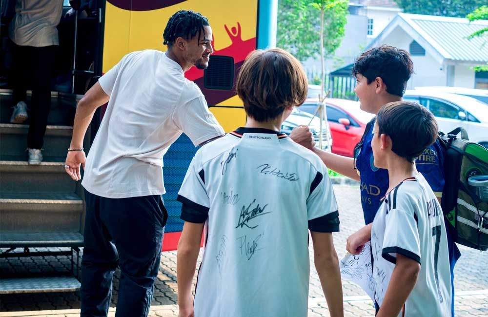 A group of young boys are standing next to each other in front of a bus.