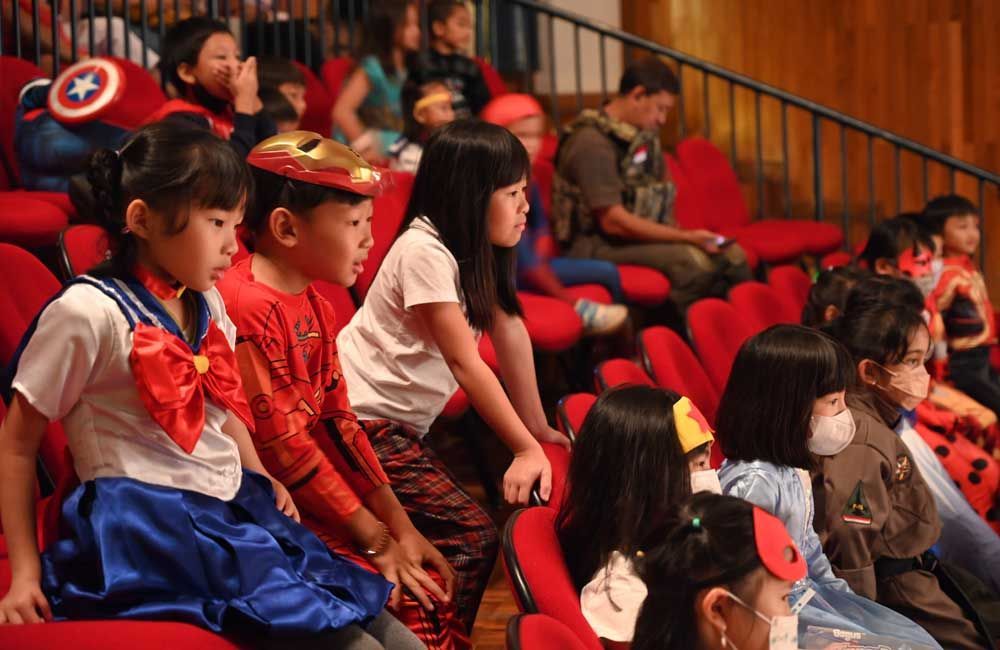 A group of children dressed in costumes are sitting in a theater.