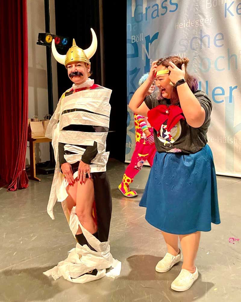 A man wrapped in toilet paper is standing next to a woman
