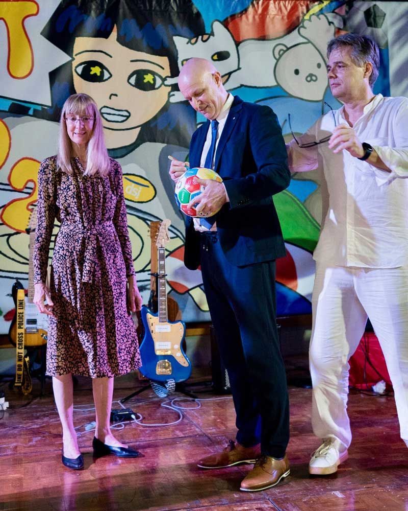 A man in a suit is holding a ball while standing next to a woman in a dress.