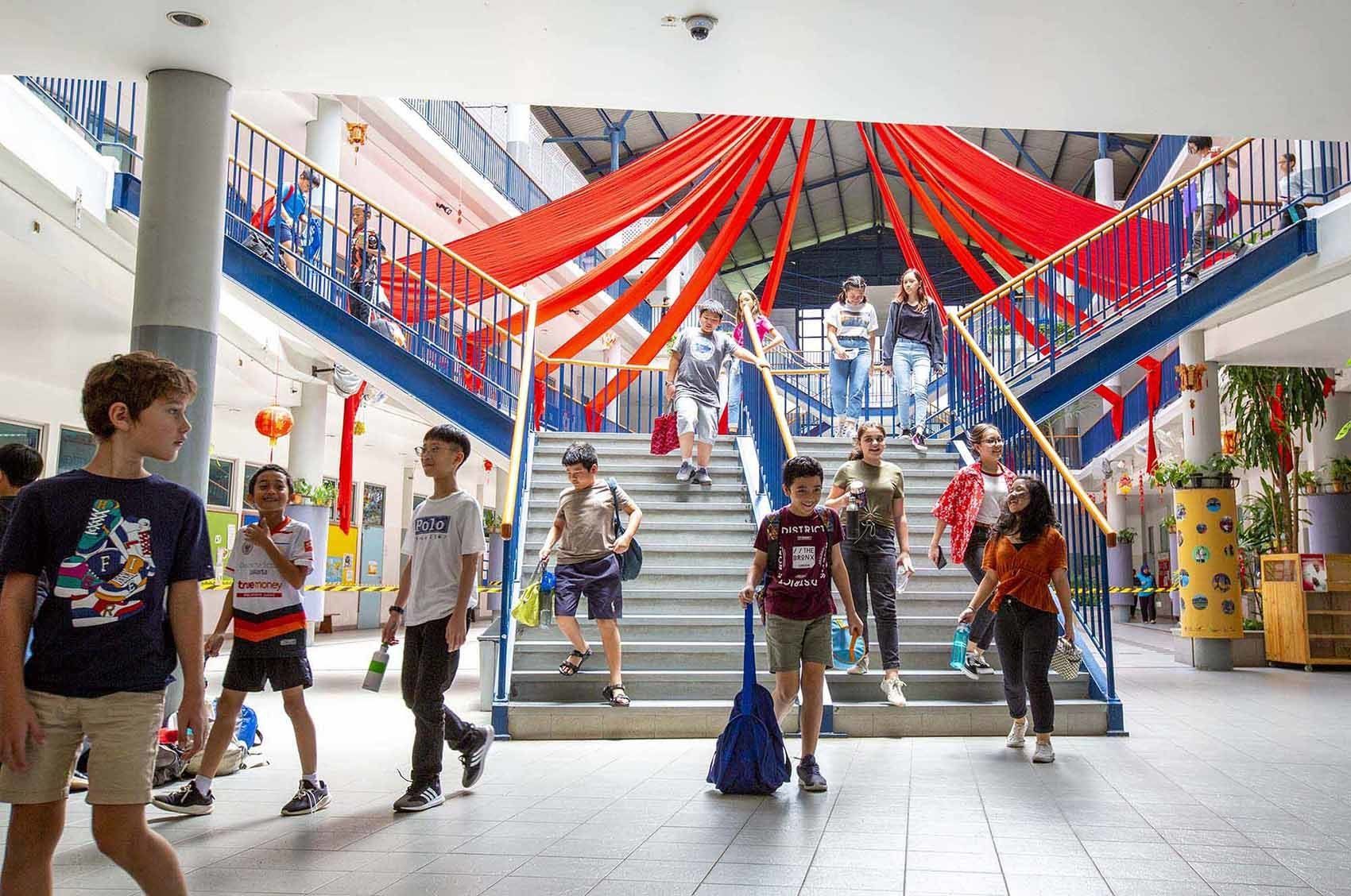 A group of people are walking down stairs in a school building.