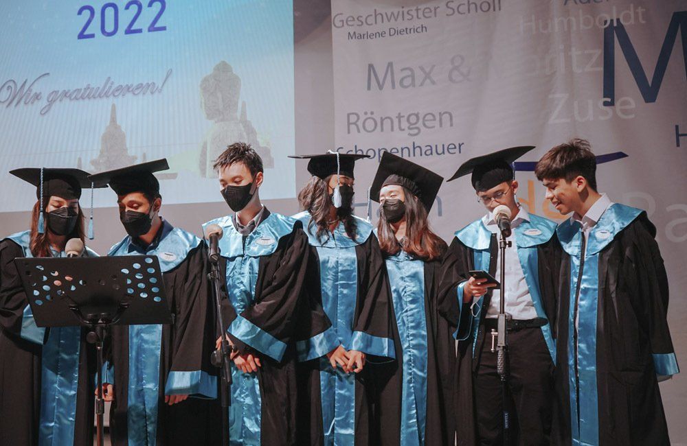 A group of graduates are standing in front of microphones on a stage.