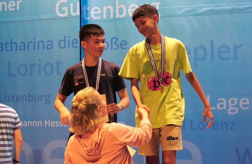 A woman shakes hands with a young man on a podium