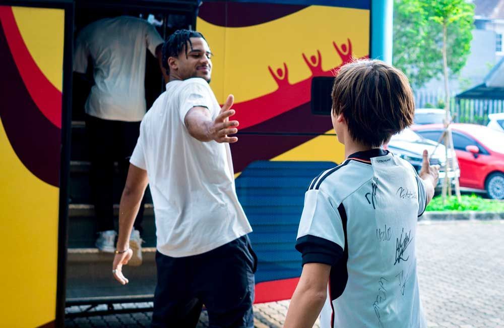 A man and a boy are standing next to each other in front of a bus.