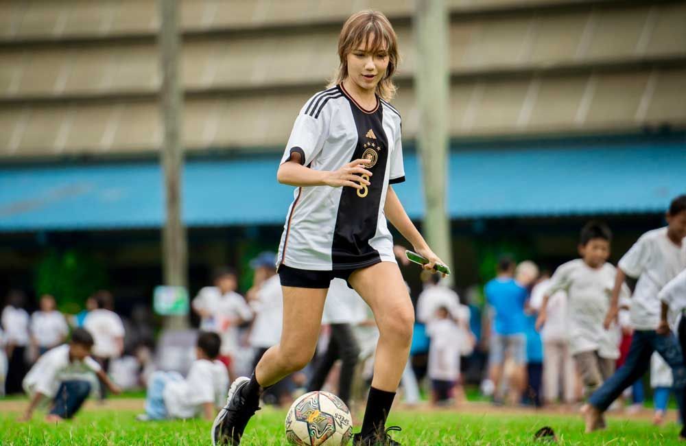 A young girl is kicking a soccer ball on a field.