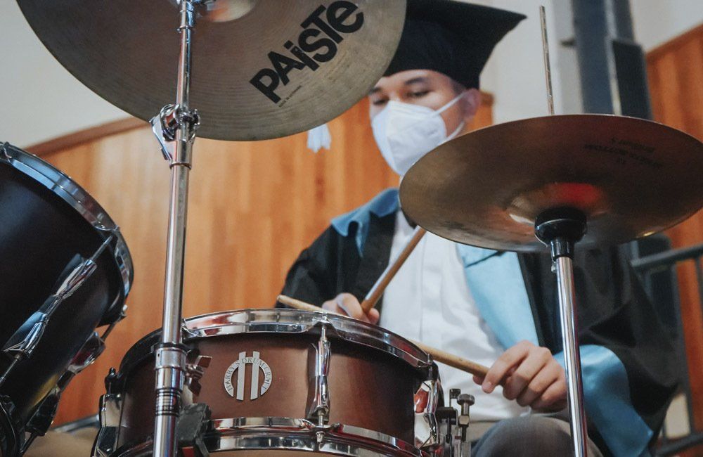 A man wearing a mask is playing drums with paiste cymbals