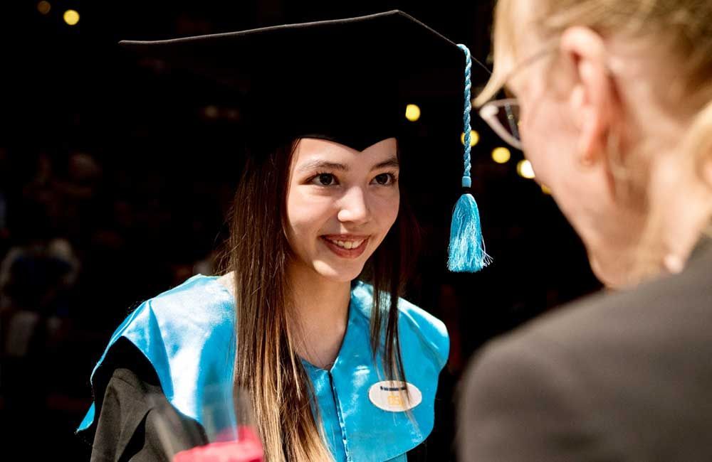 A woman in a graduation cap and gown is talking to a man.