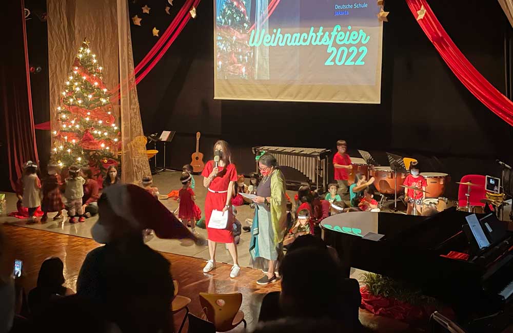 A group of people are standing on a stage in front of a christmas tree.