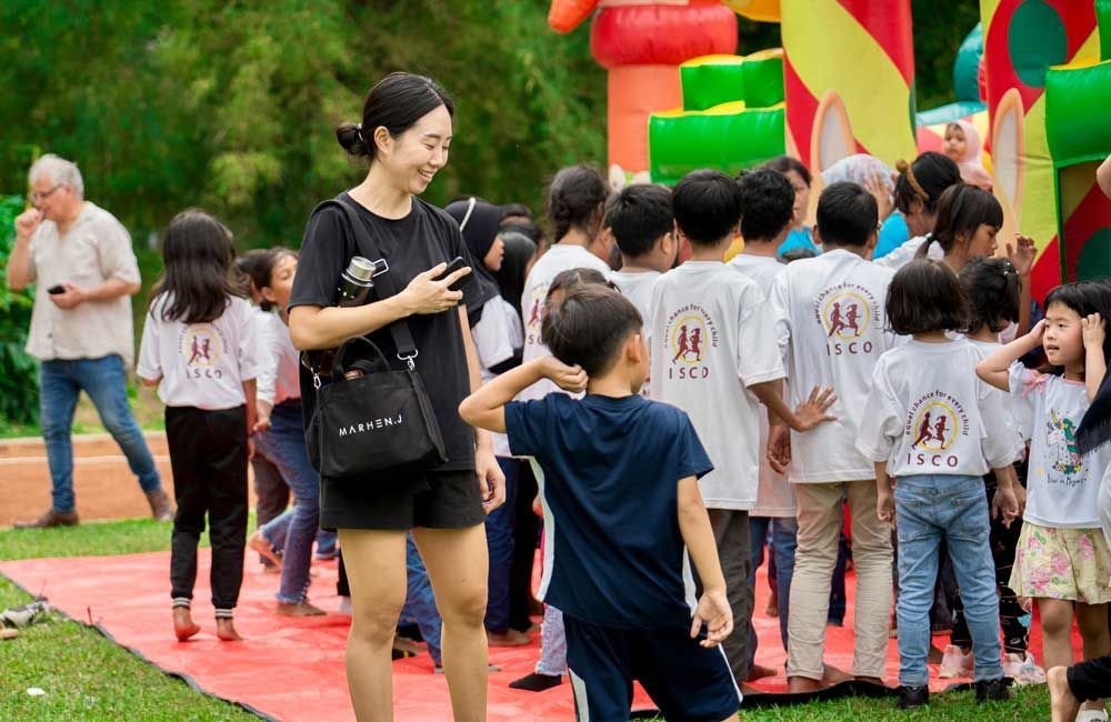 A woman is standing in front of a group of children in front of a bouncy house.