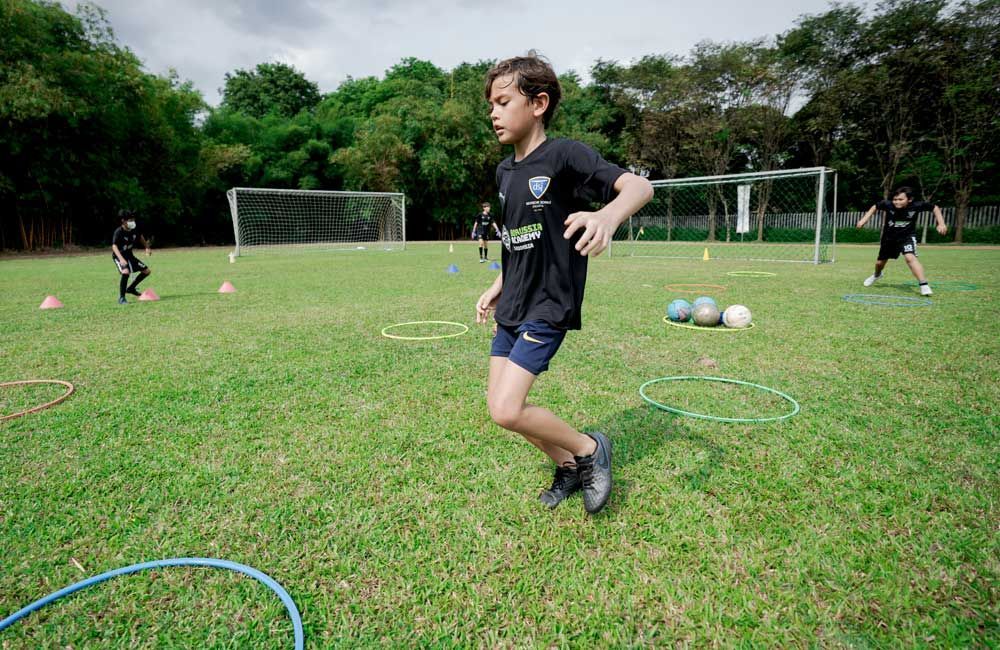 A young boy is running through a hula hoop on a soccer field.