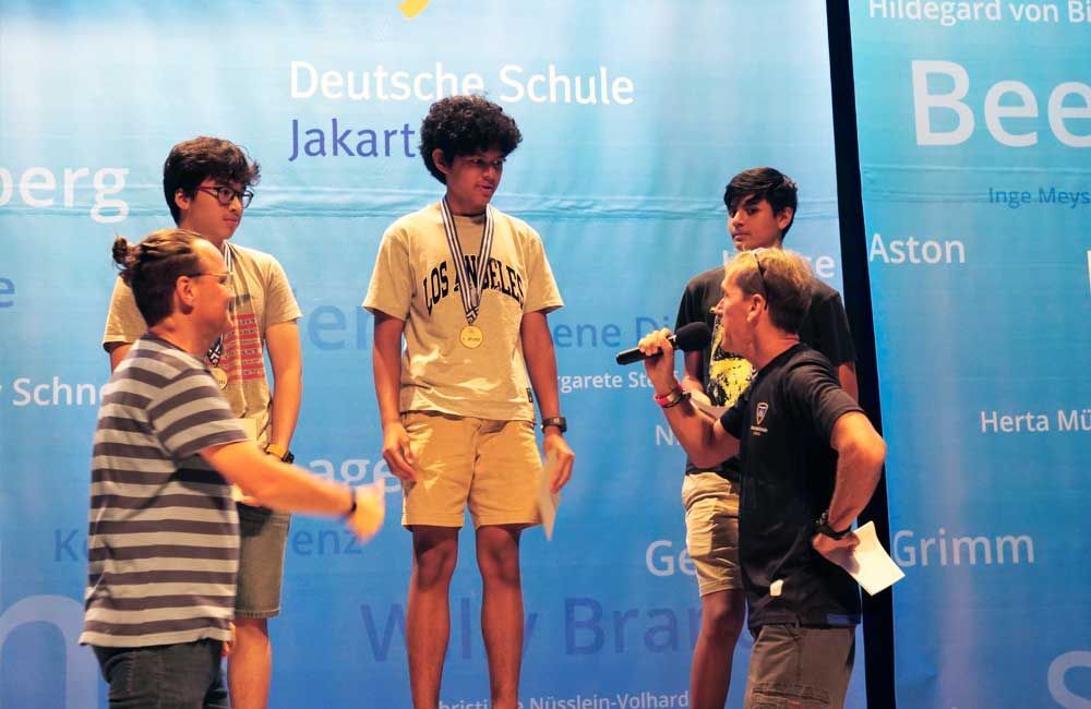 A group of people standing in front of a sign that says deutsche schule