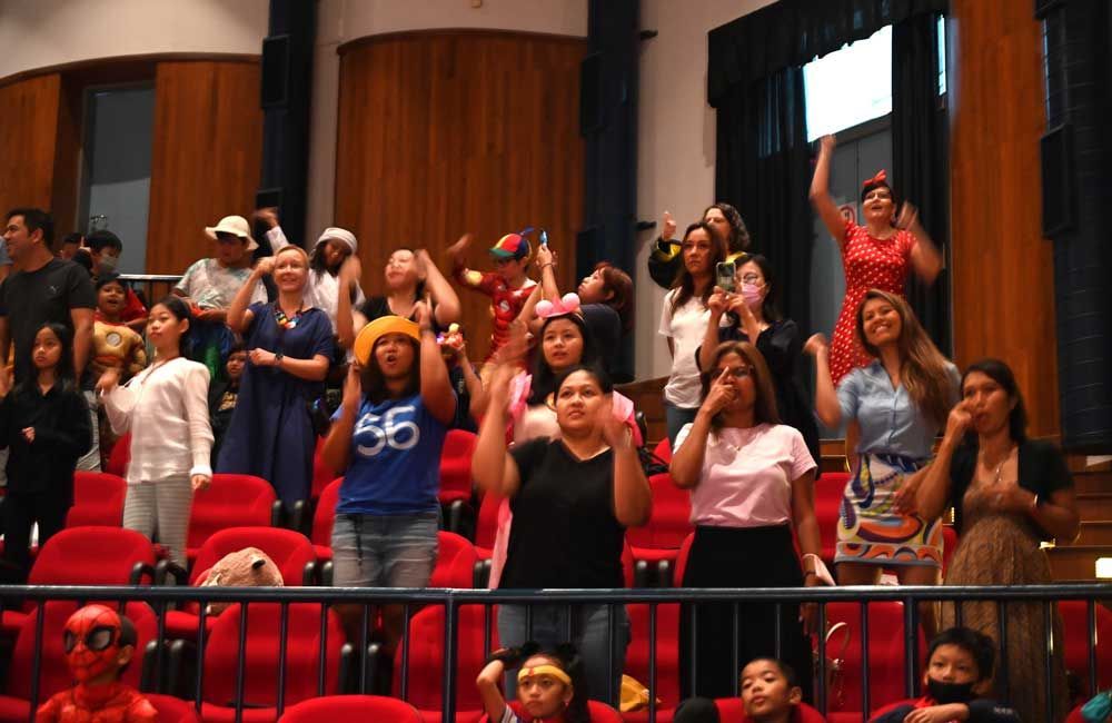 A group of people are standing in a stadium with their hands in the air.