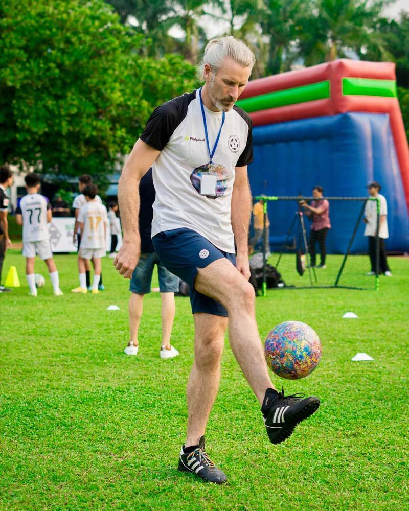 A man is kicking a soccer ball on a field.