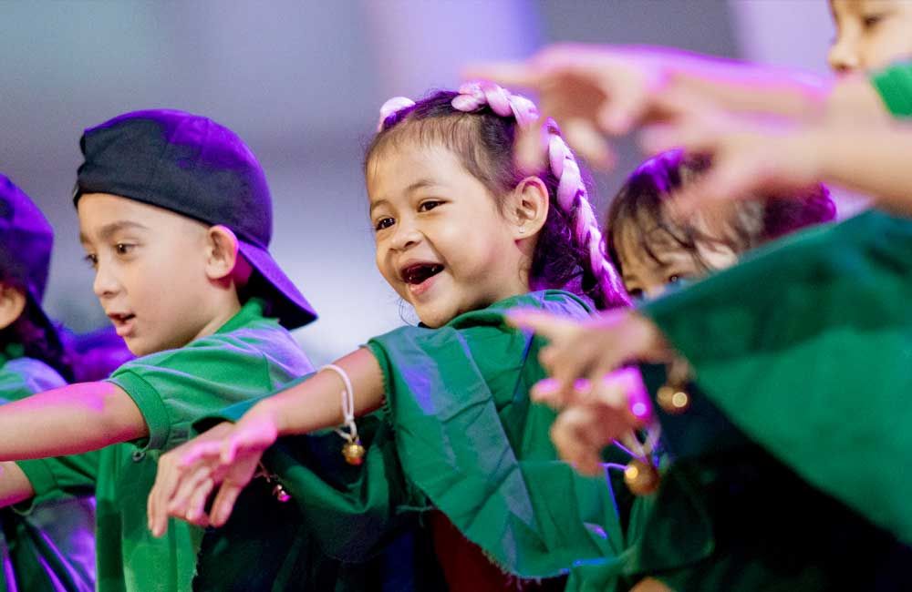 A group of young children are dancing together on a stage.