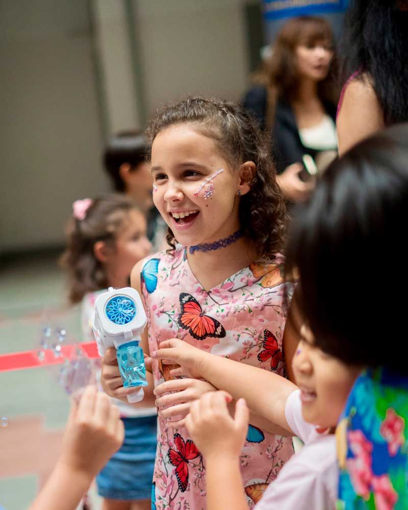 A little girl with butterfly paint on her face is holding a microphone.