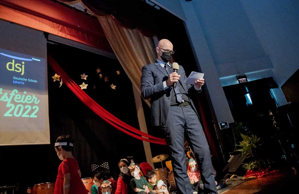 A man in a suit is standing on a stage holding a microphone.