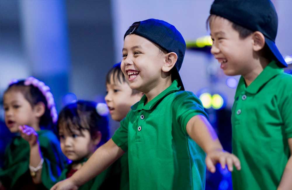 A group of young children wearing green shirts and hats are standing next to each other.