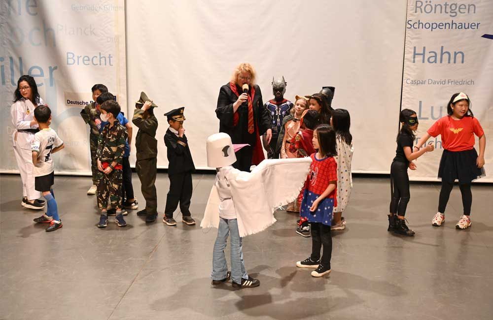 A group of children dressed in costumes are standing on a stage.