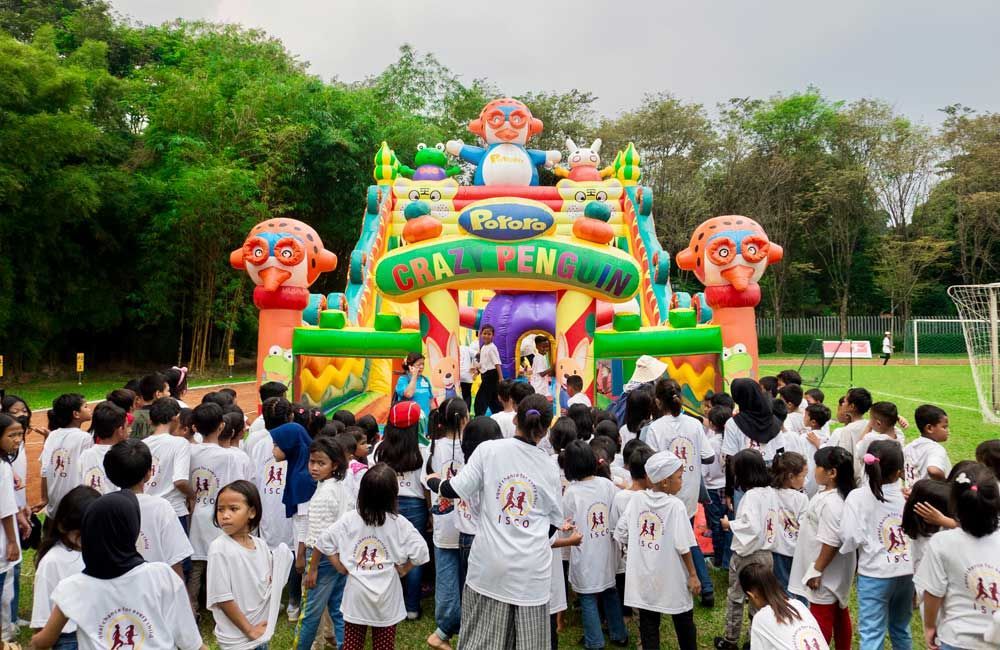 A large group of children are standing in front of a bouncy house.