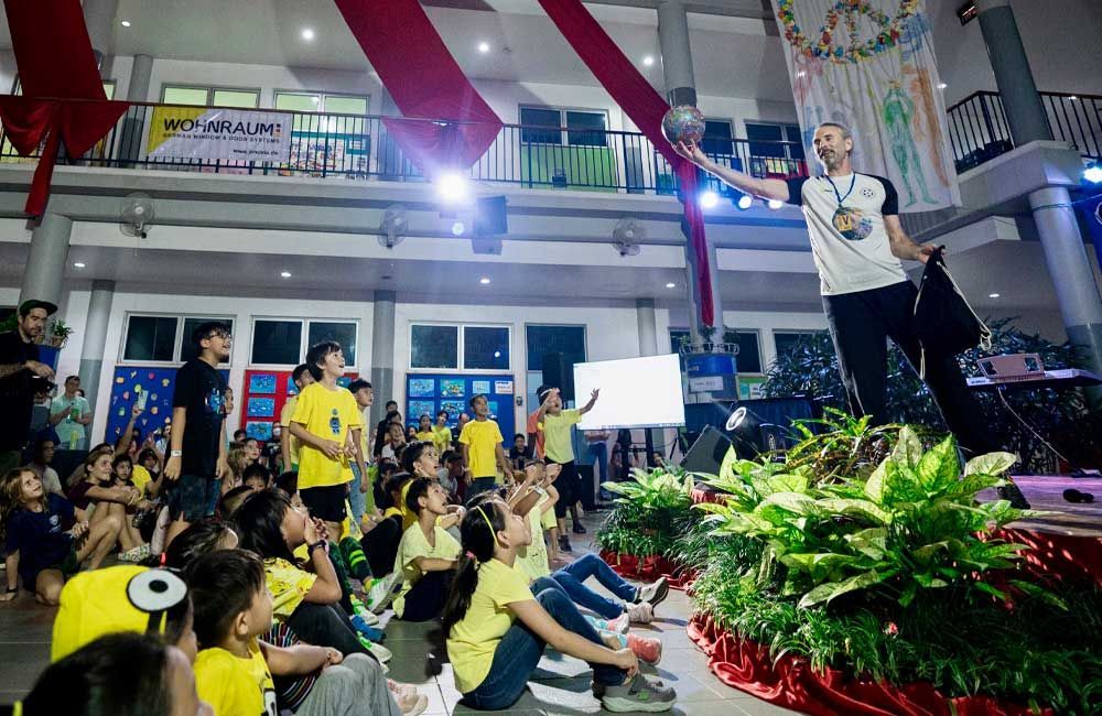 A man is standing on a stage holding a torch in front of a crowd of people.