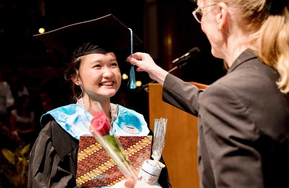 A woman is putting a tassel on a graduate 's cap