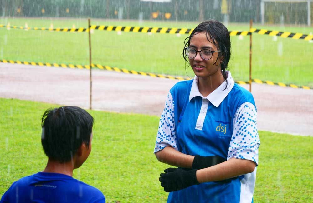 A woman in a blue shirt is talking to a boy in a blue shirt in the rain.