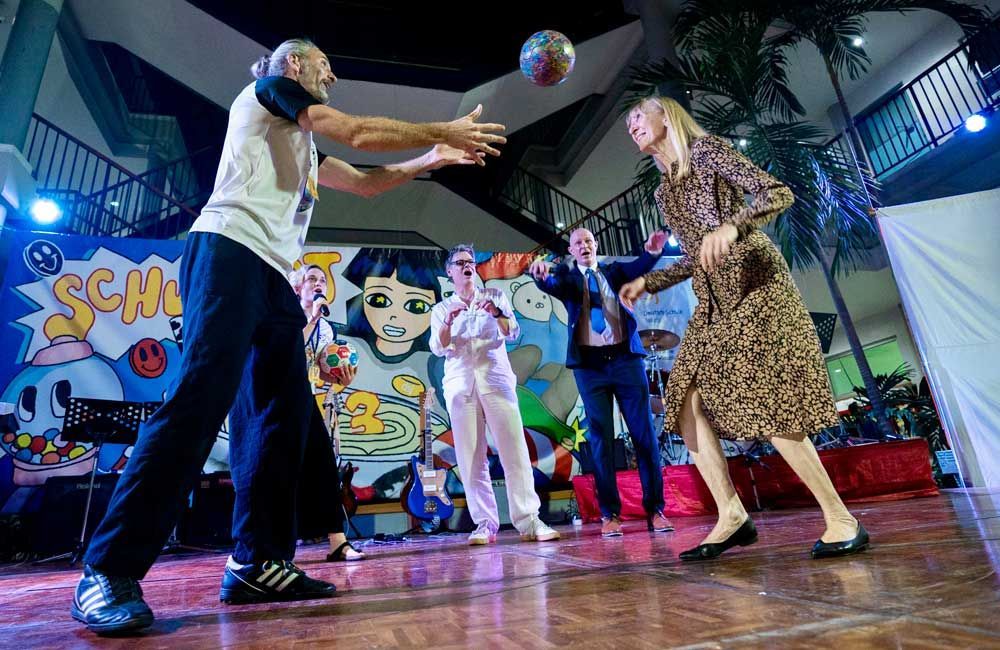 A group of people are dancing on a stage in front of a graffiti wall.