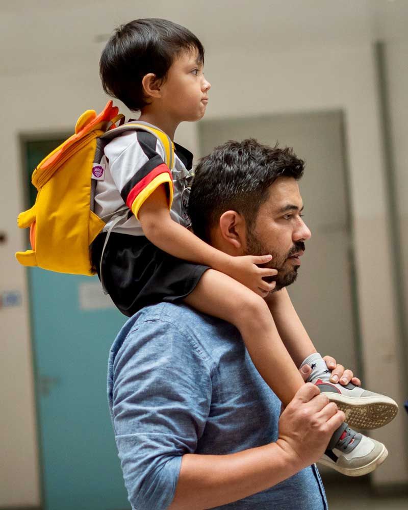 A man is carrying a little boy on his shoulders.