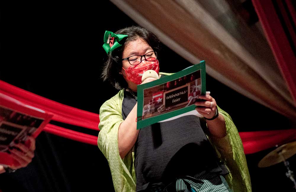 A woman wearing a mask and glasses is holding a piece of paper.