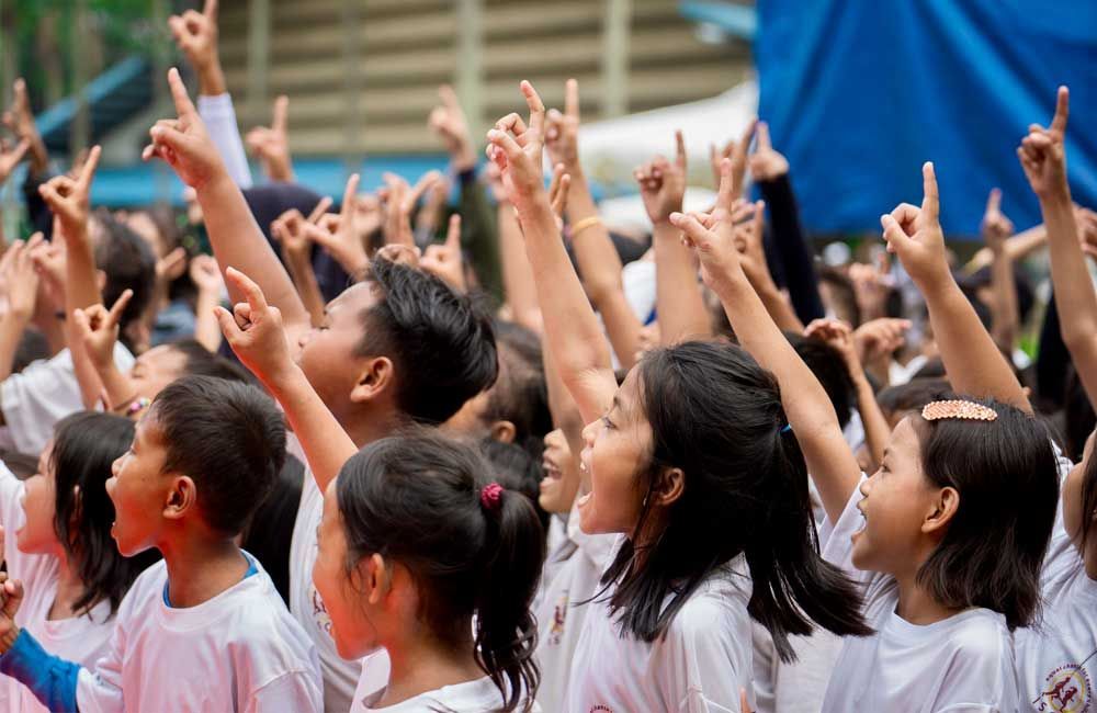 A group of children are raising their hands in the air.