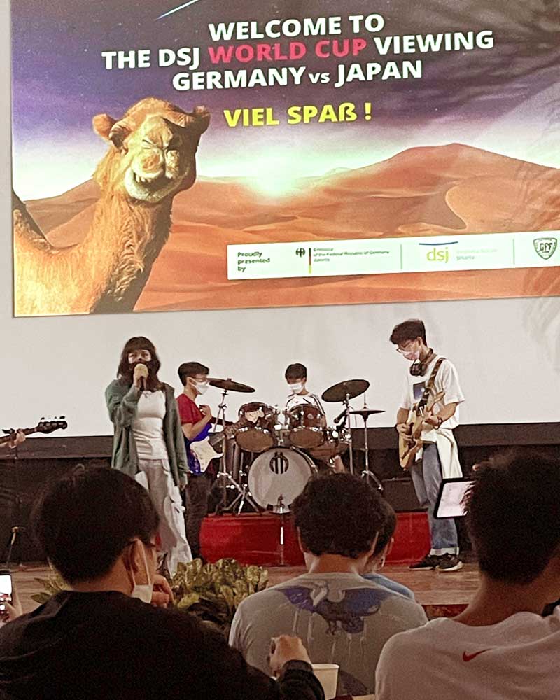 A group of people are sitting in front of a large screen with a camel on it.